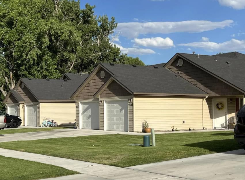 A row of houses with cars parked in front of them.