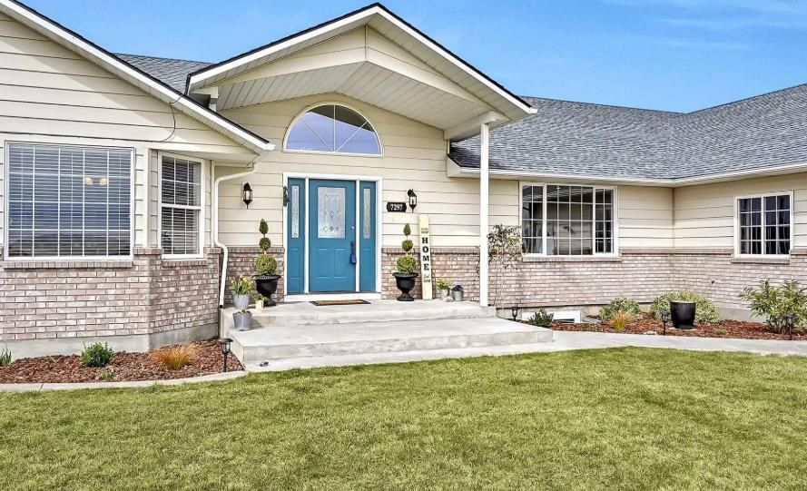 A white house with a blue door and a large lawn in front of it.