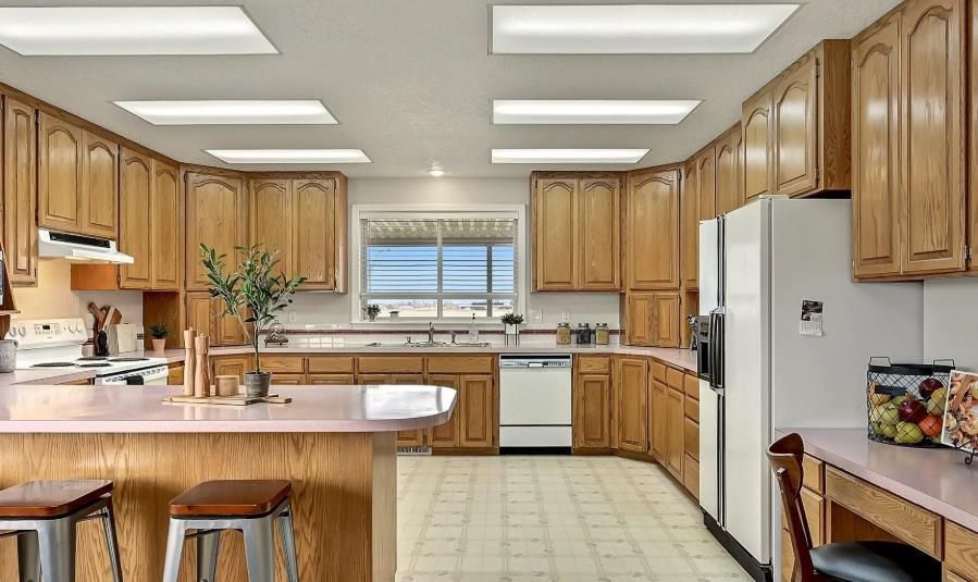 A kitchen with wooden cabinets, a refrigerator, a dishwasher, and a window.