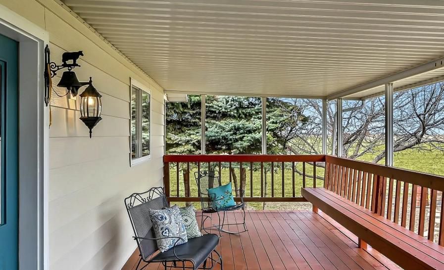 A screened in porch with a bench and chairs on it.