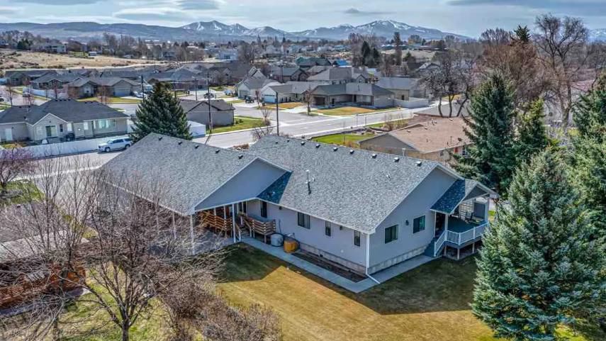An aerial view of a house in a residential area with mountains in the background.