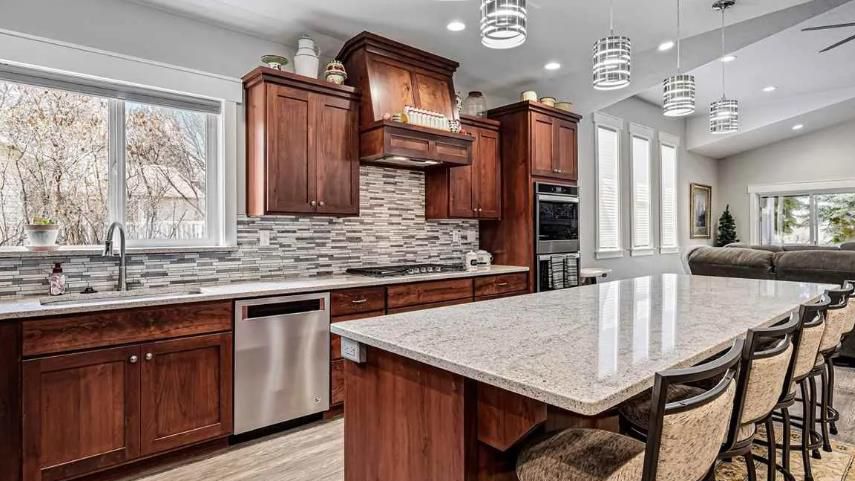 A kitchen with wooden cabinets, granite counter tops, stainless steel appliances and a large island.
