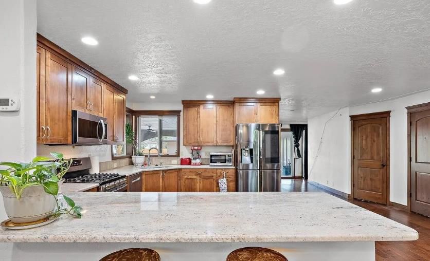 A kitchen with wooden cabinets, granite counter tops, stainless steel appliances and a large island.