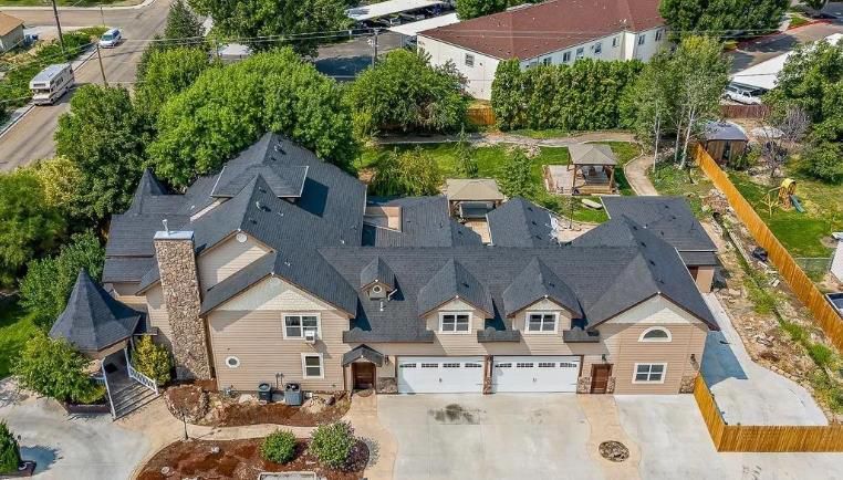 An aerial view of a large house with three garages surrounded by trees.