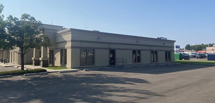 A building with a lot of windows and a parking lot in front of it.