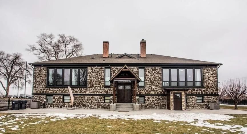 A large stone house is sitting in the middle of a snowy field.