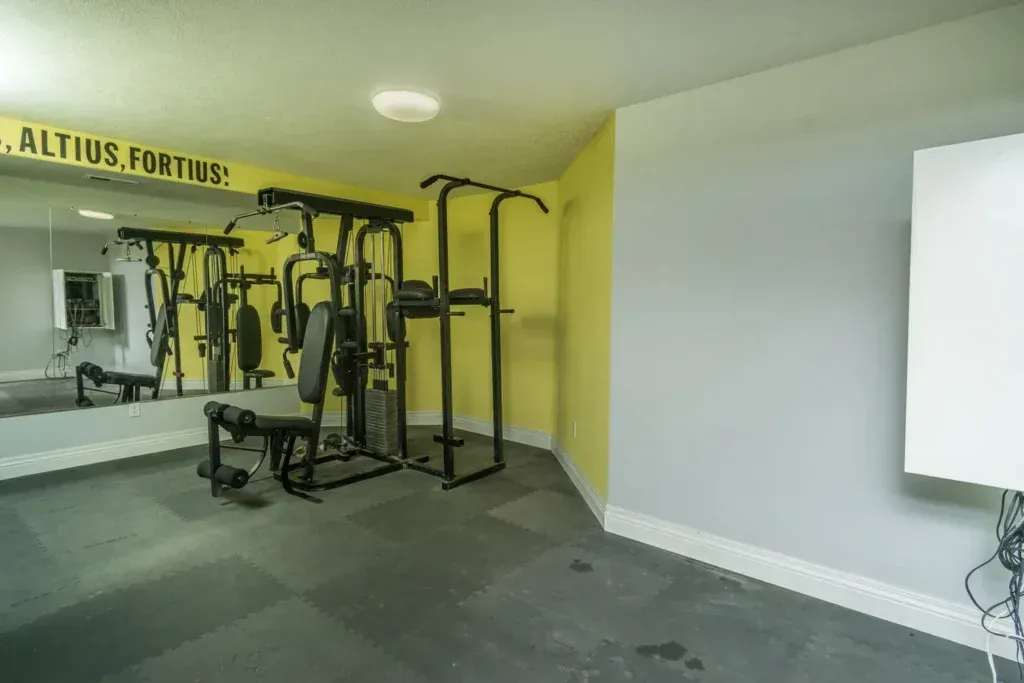A gym with a lot of equipment and a large mirror.
