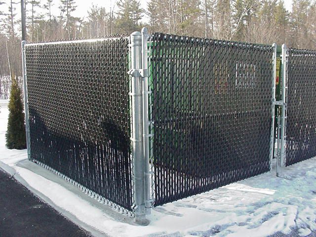 Black chain-link fenced enclosure in a snowy outdoor area with trees in the background