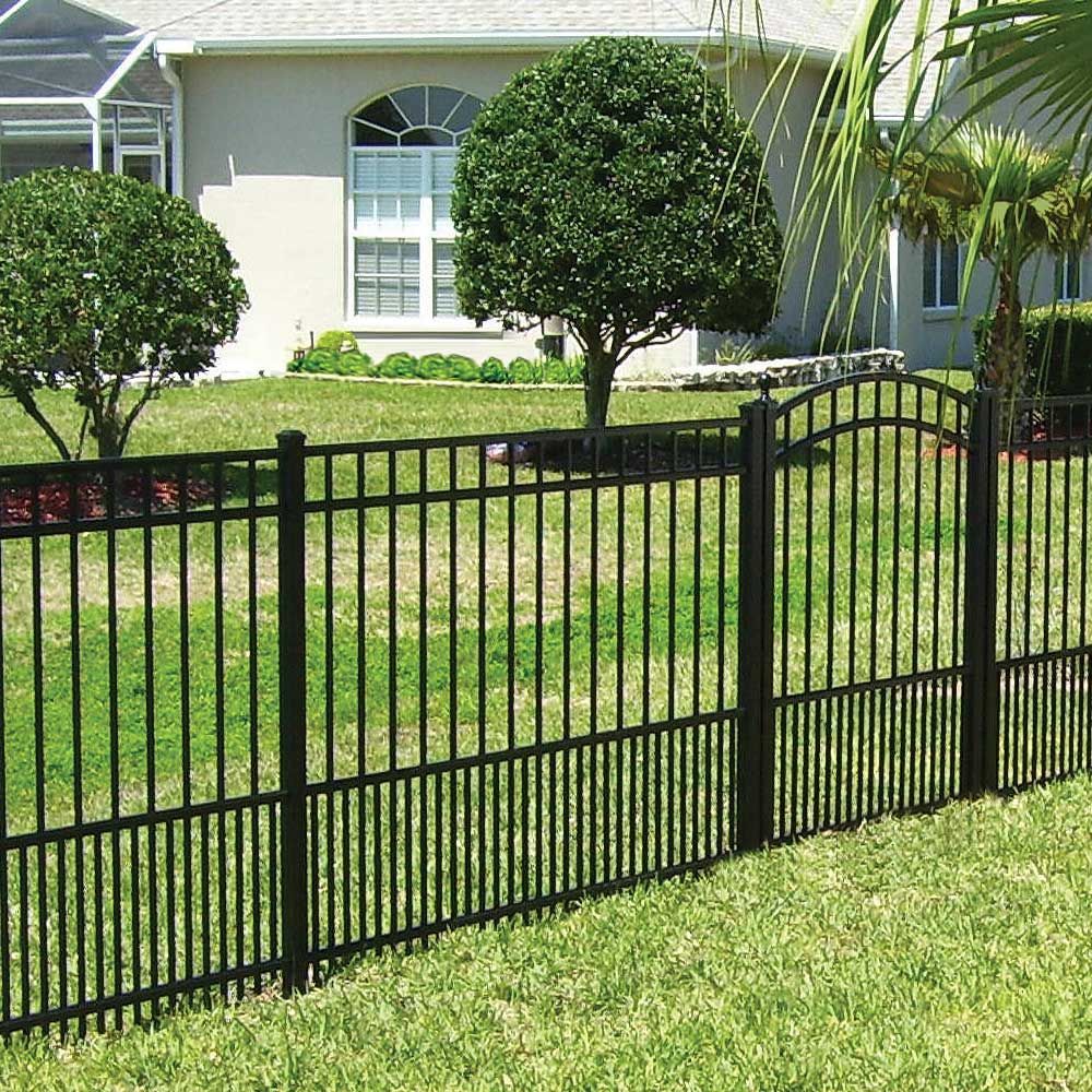 Black metal fence in a green front yard with trimmed trees and a house in the background