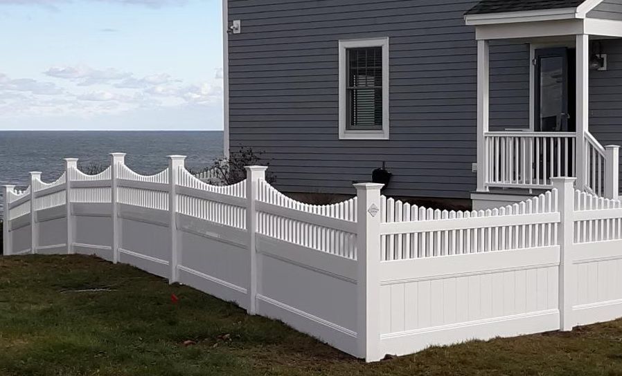 White vinyl fence along a gray house by the ocean