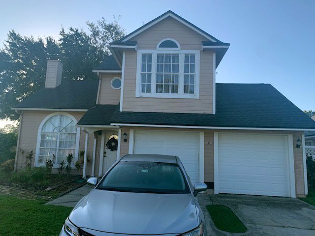 Suburban two-story house with a silver car parked in the driveway at dusk