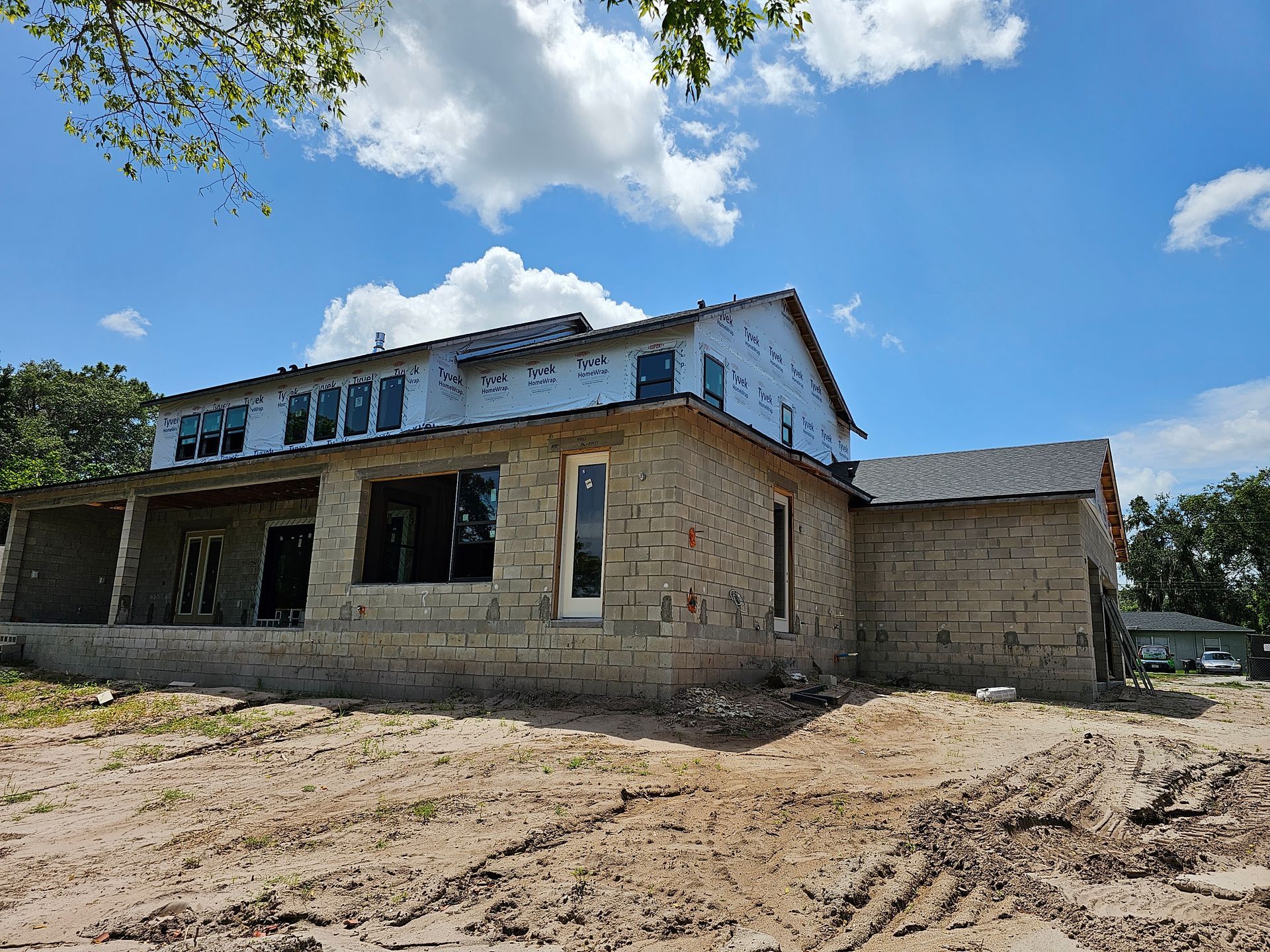 Abandoned two-story stone building under a blue sky, with a dirt foreground and cloudy weather