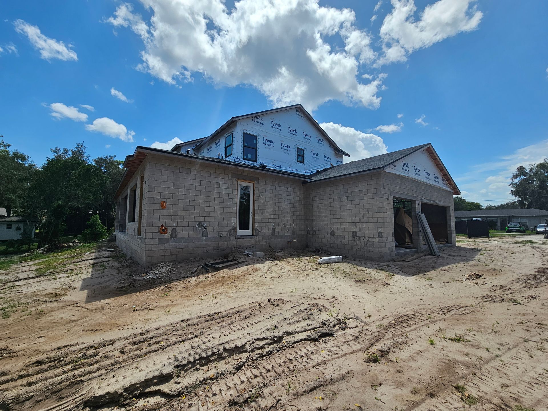 Partially built house with exposed brick walls and white upper siding under a blue sky