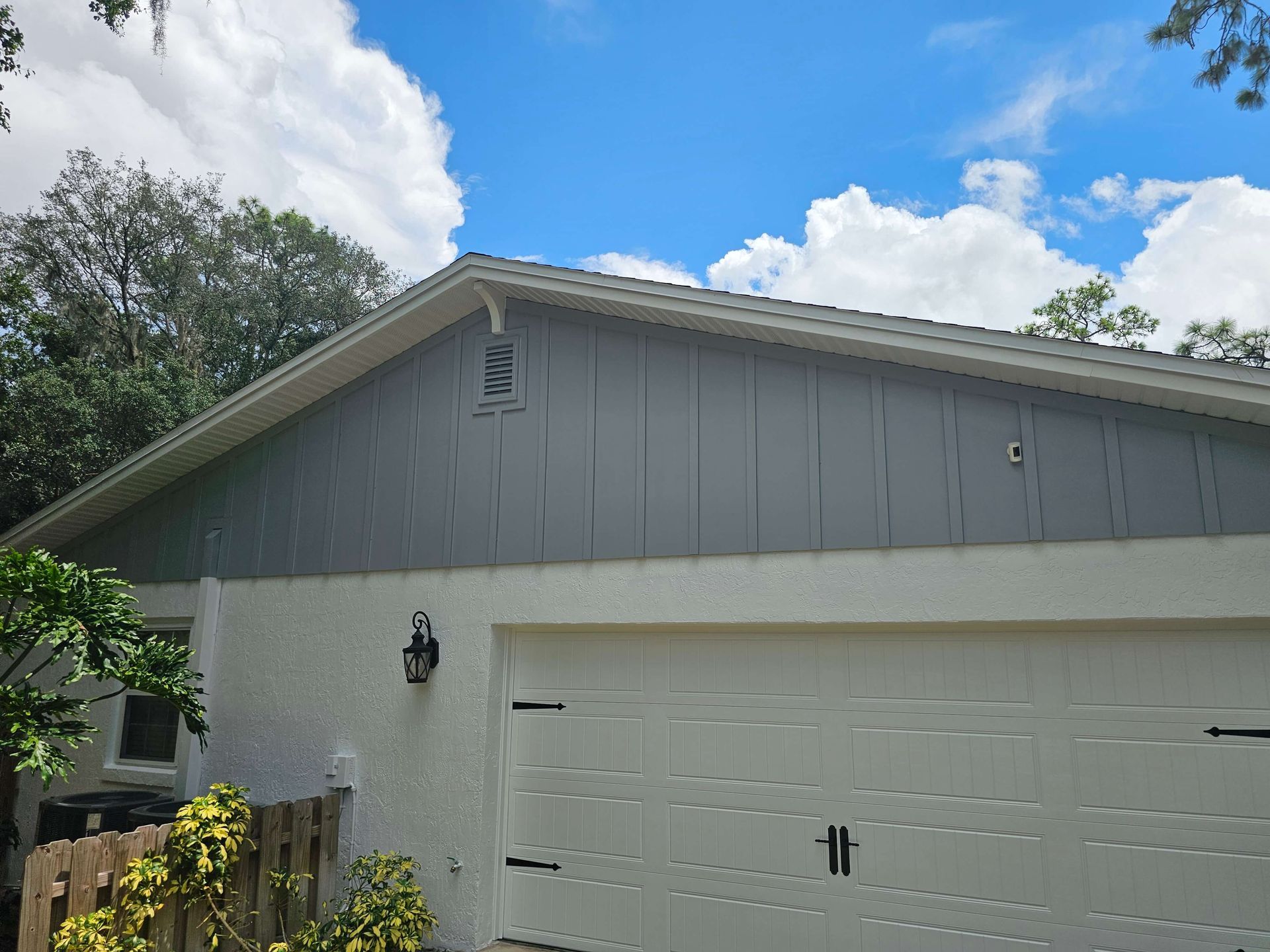 Gray house exterior with white garage door and blue sky above