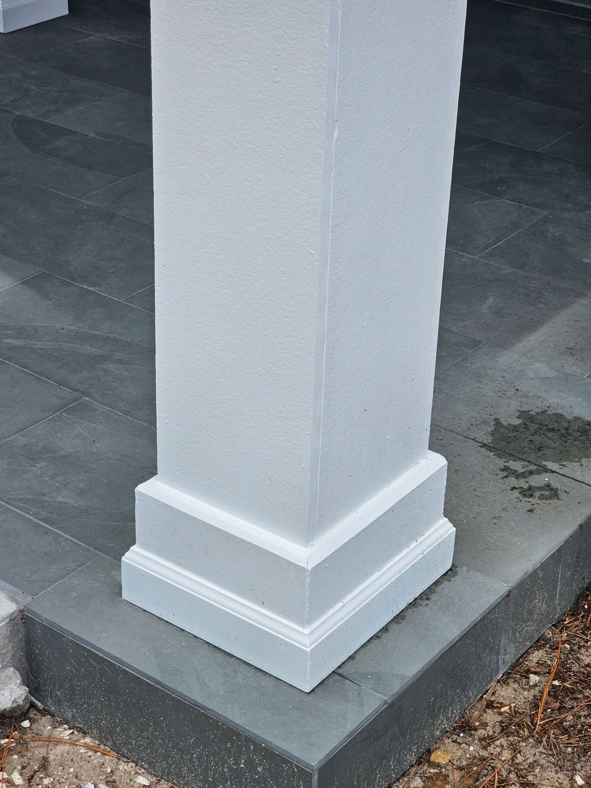 White square porch column on a gray concrete base, showing decorative trim detail.