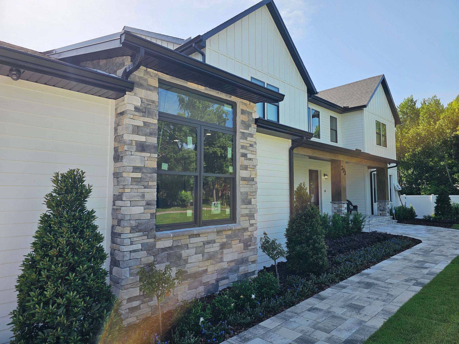 Modern two-story house exterior with stone accents, large windows, and a landscaped front walkway