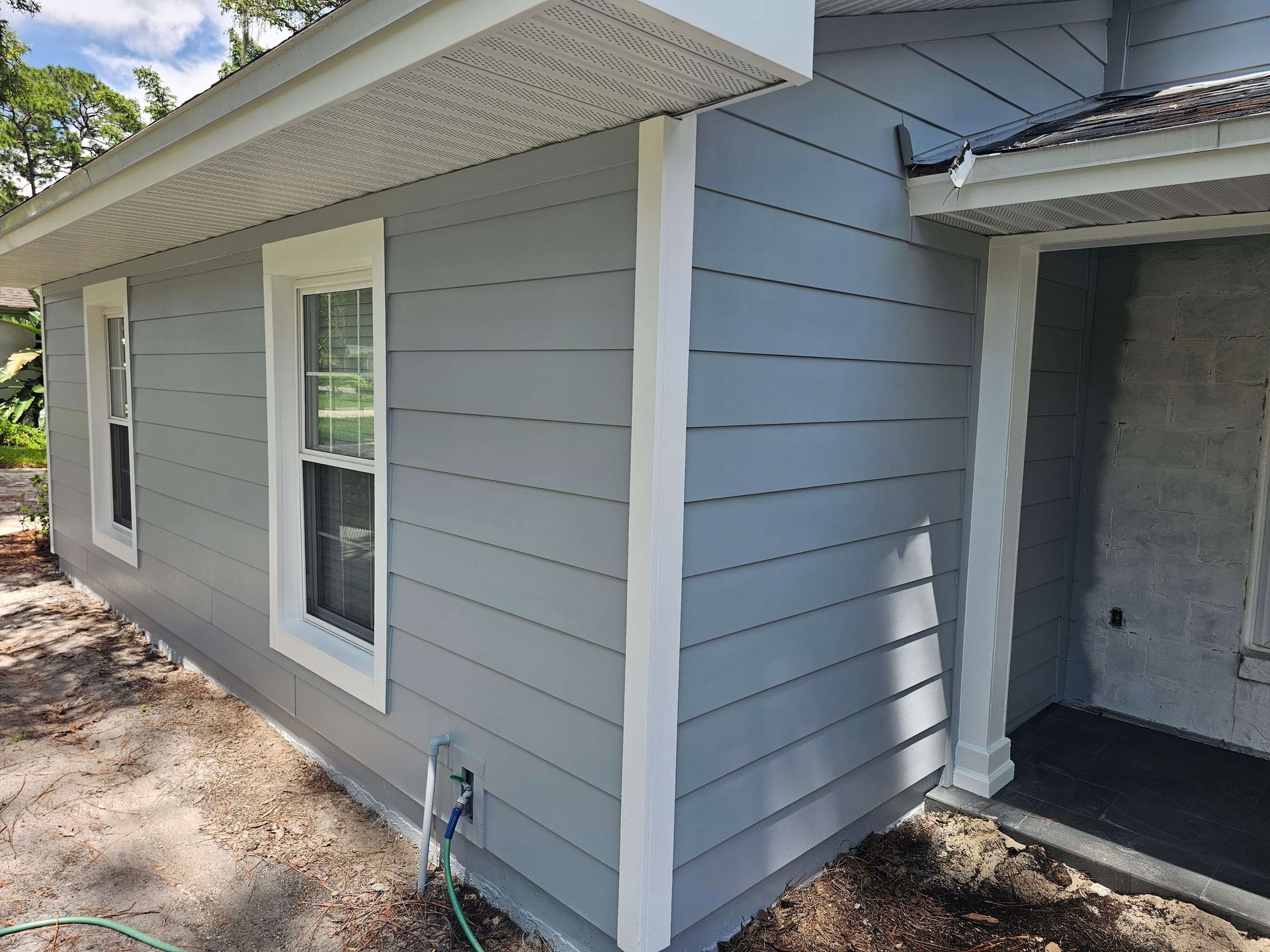 Gray house exterior with white trim, window, and covered entry porch.