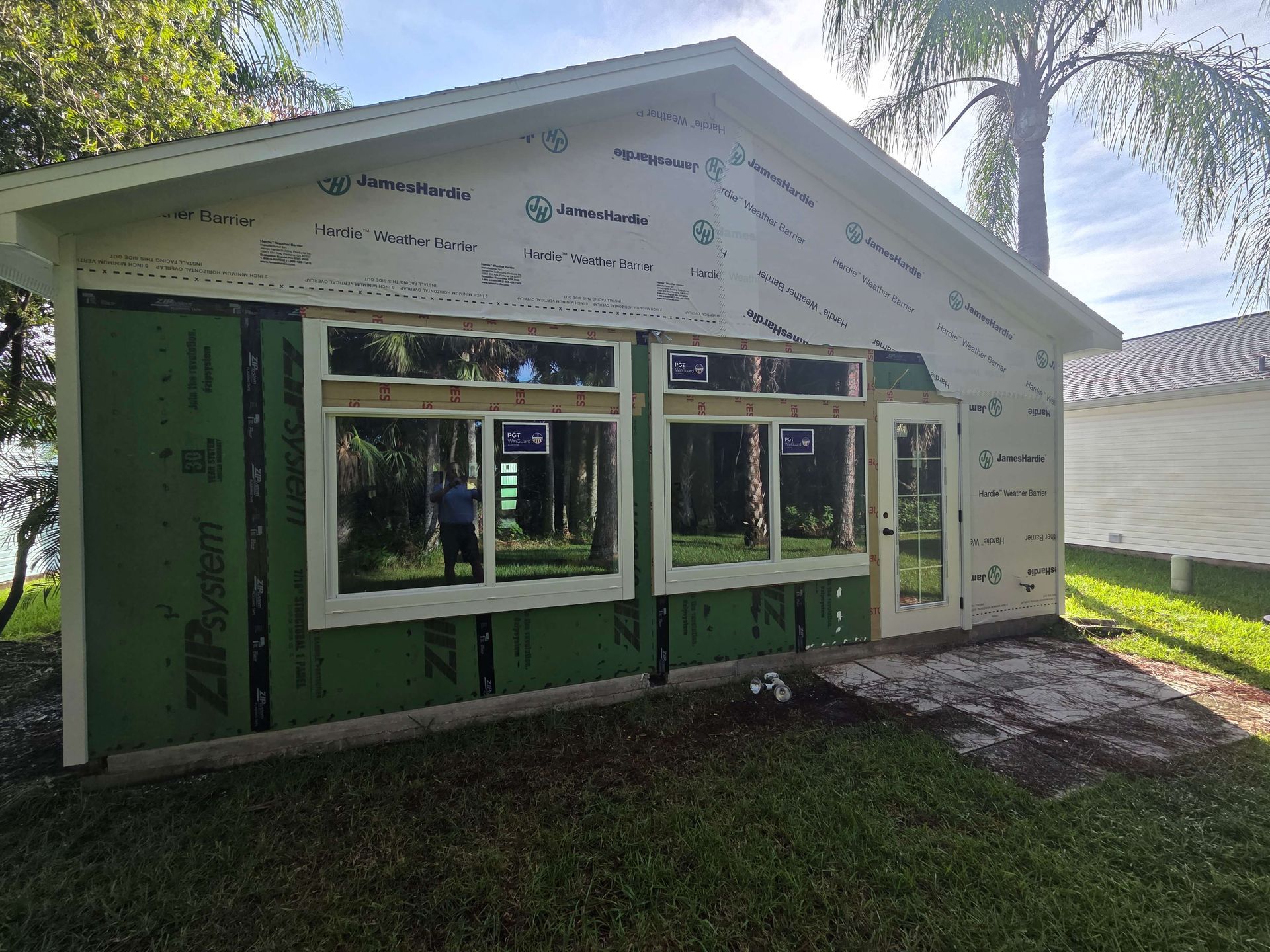 Partially built house with green sheathing, window openings, and a front porch under construction