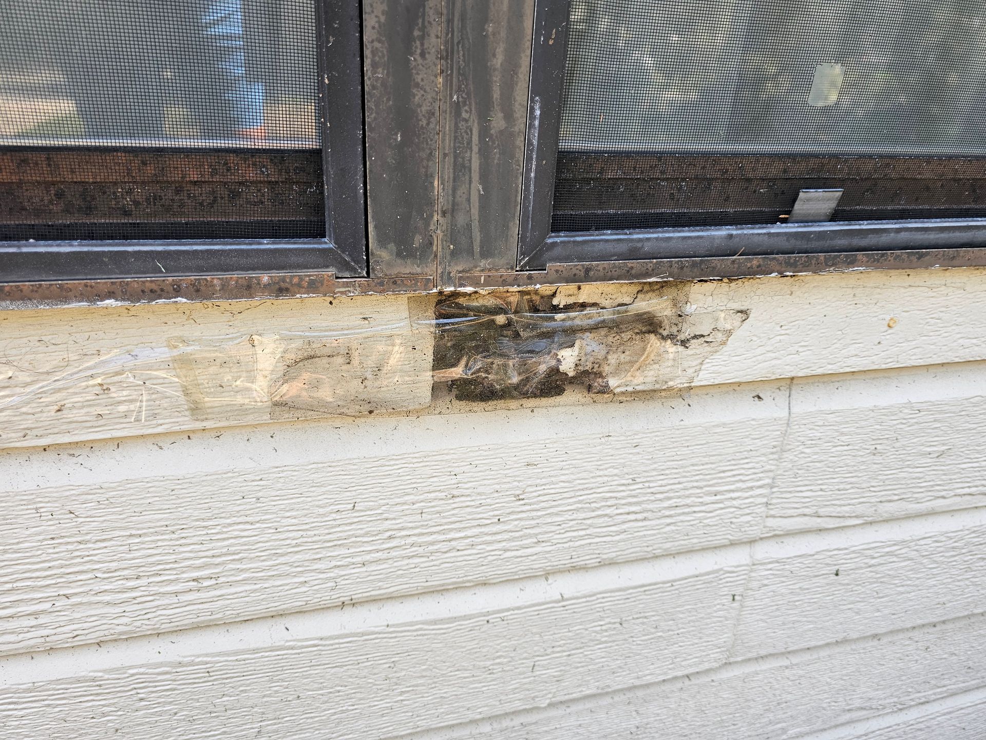 Close-up of a damaged window sill with peeling paint and dark water stains on a white wall