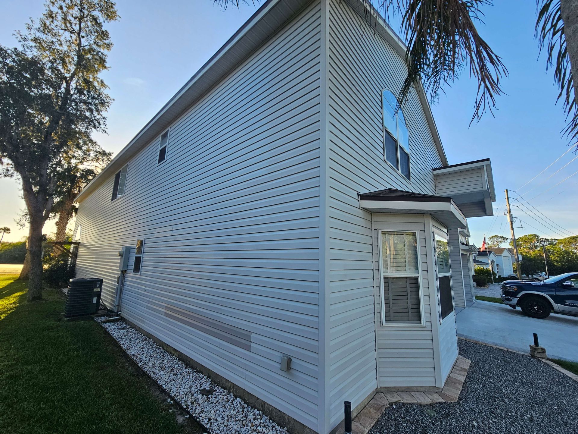 White-sided corner building with a small entryway, seen from the side beside a street and grass.