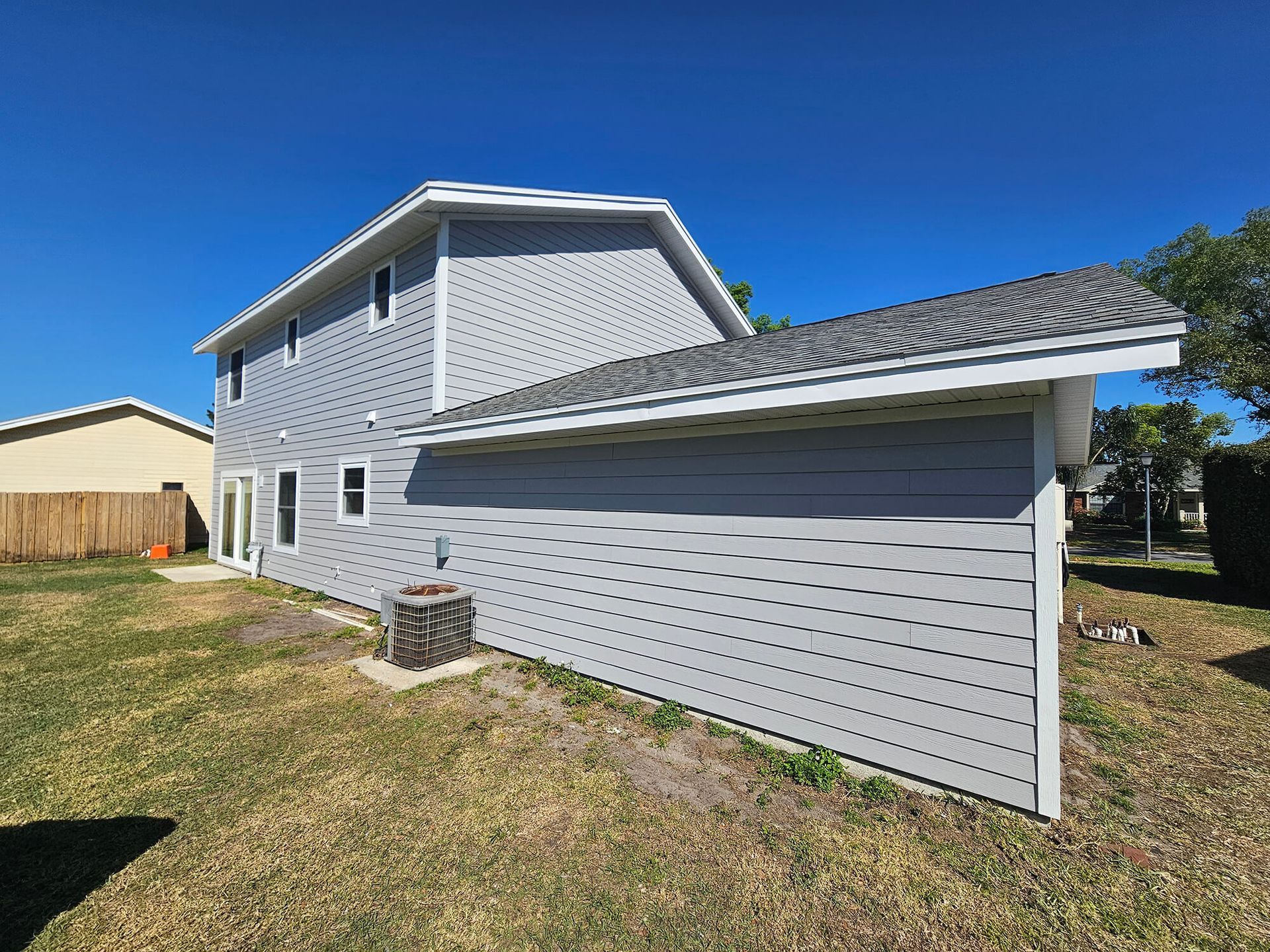 Gray two-story house exterior with screened porch and blue sky