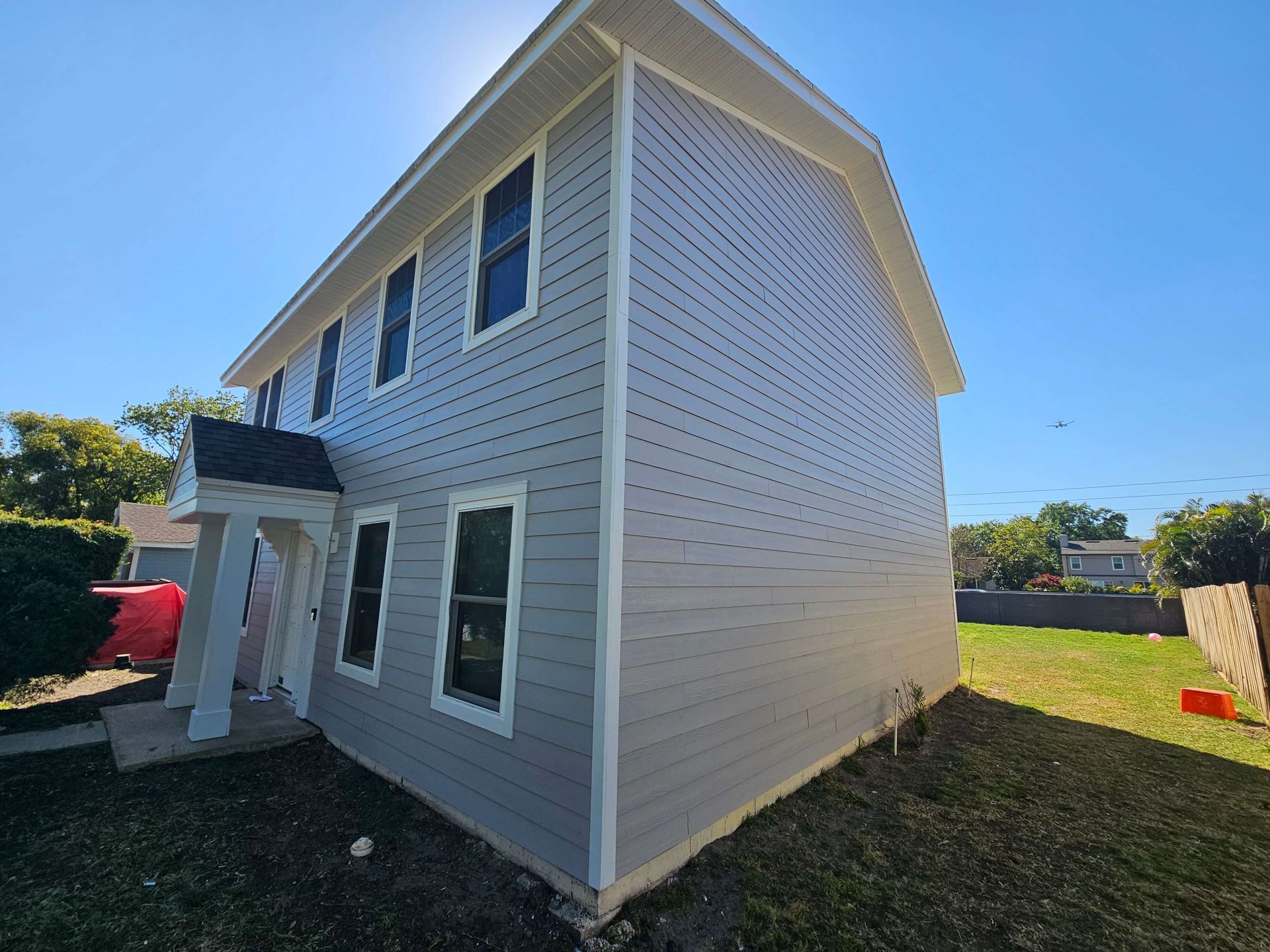 White two-story house with gray trim and white siding in a sunny yard