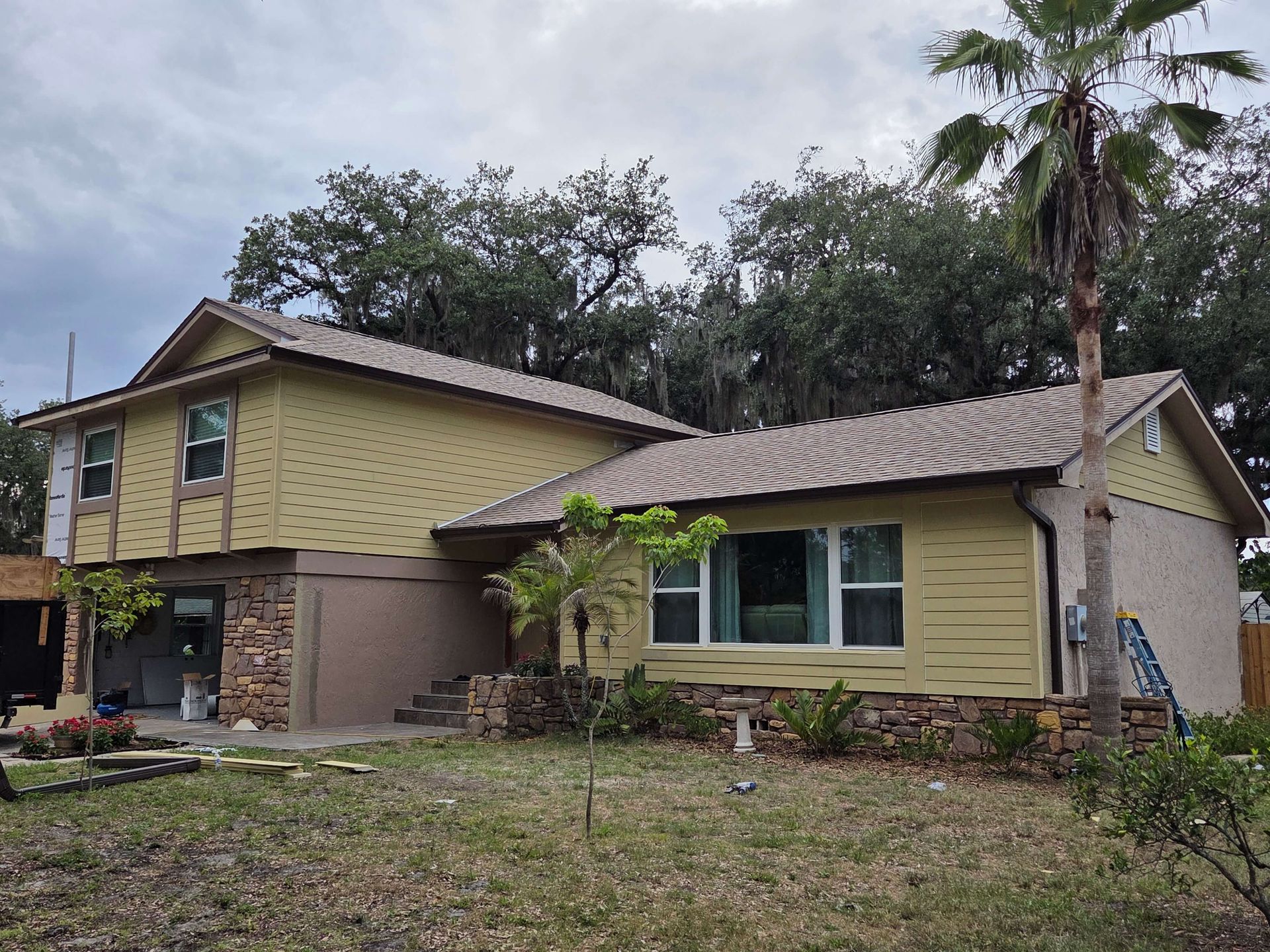 Two-story yellow house with a tiled roof and front porch in a grassy yard