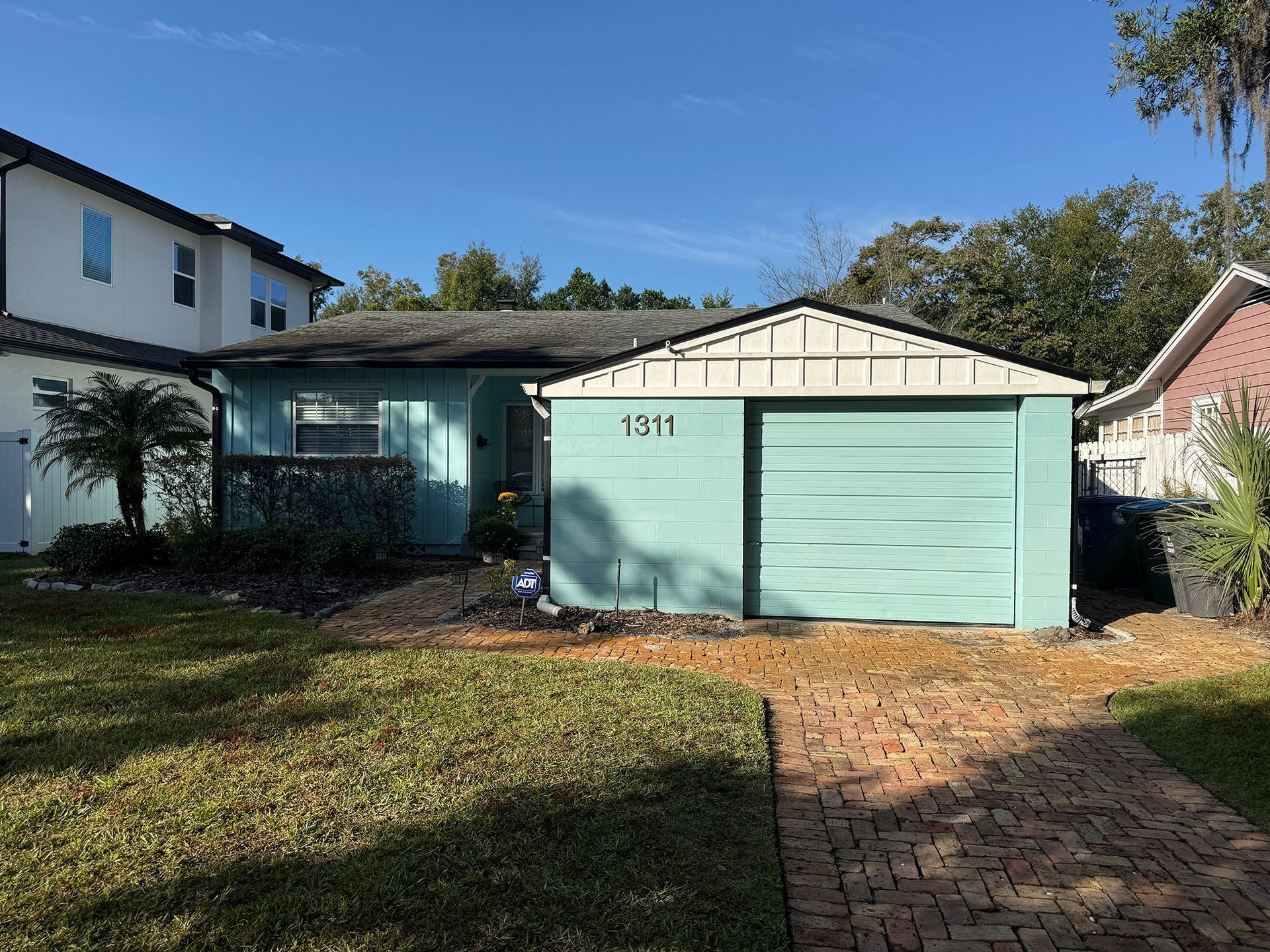 Mint-green two-car garage with driveway and front lawn in a suburban neighborhood