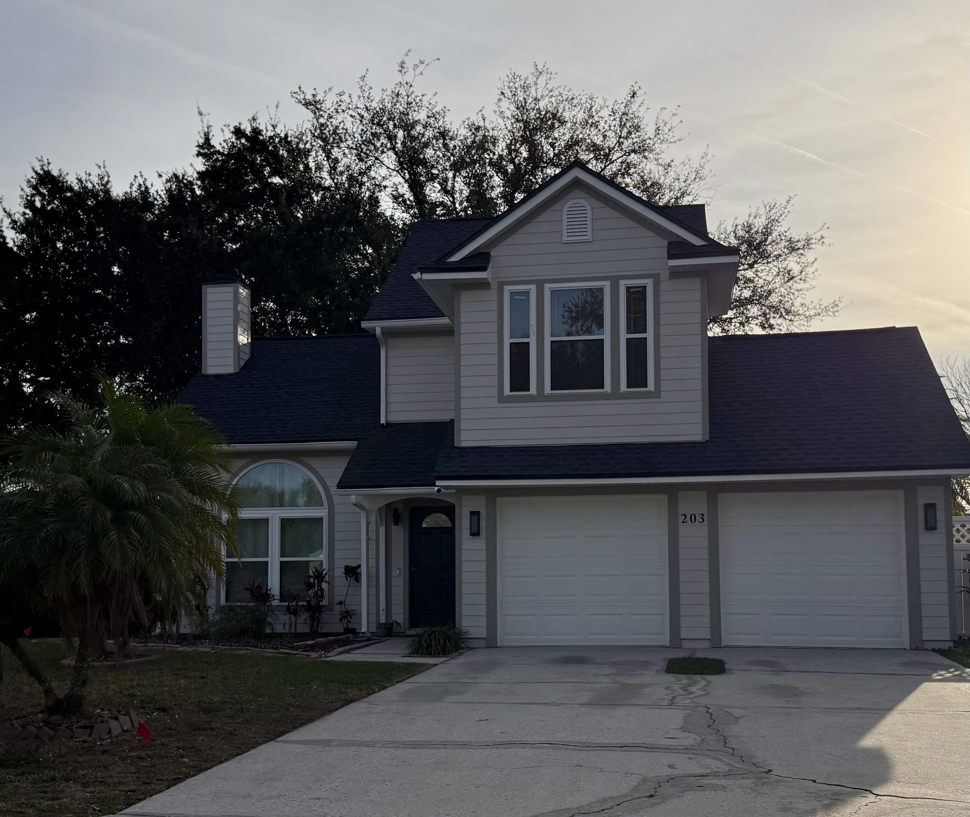 Suburban two-story house with attached garage and driveway at dusk