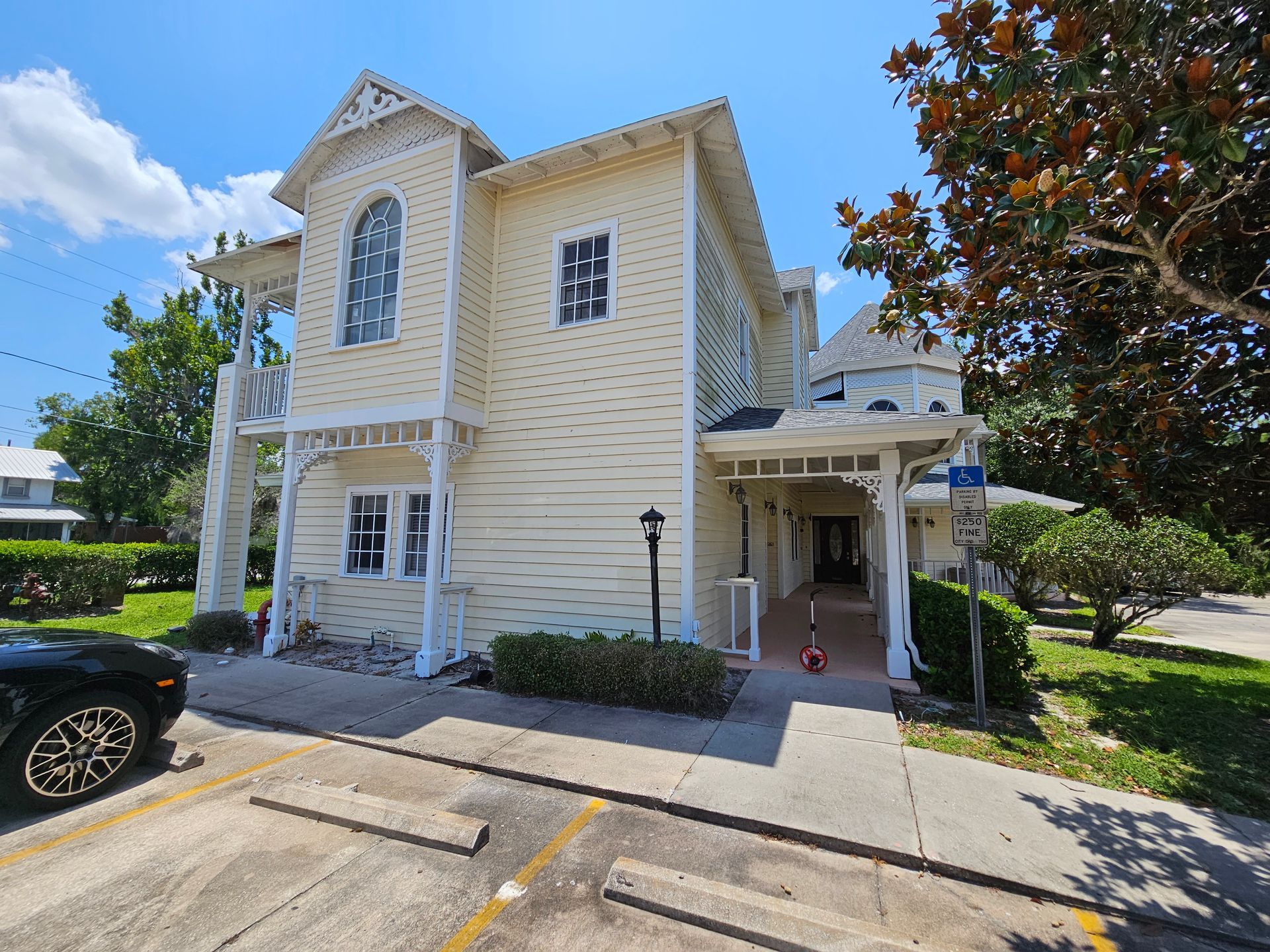Two-story beige house with white trim, front porch, and driveway under a blue sky