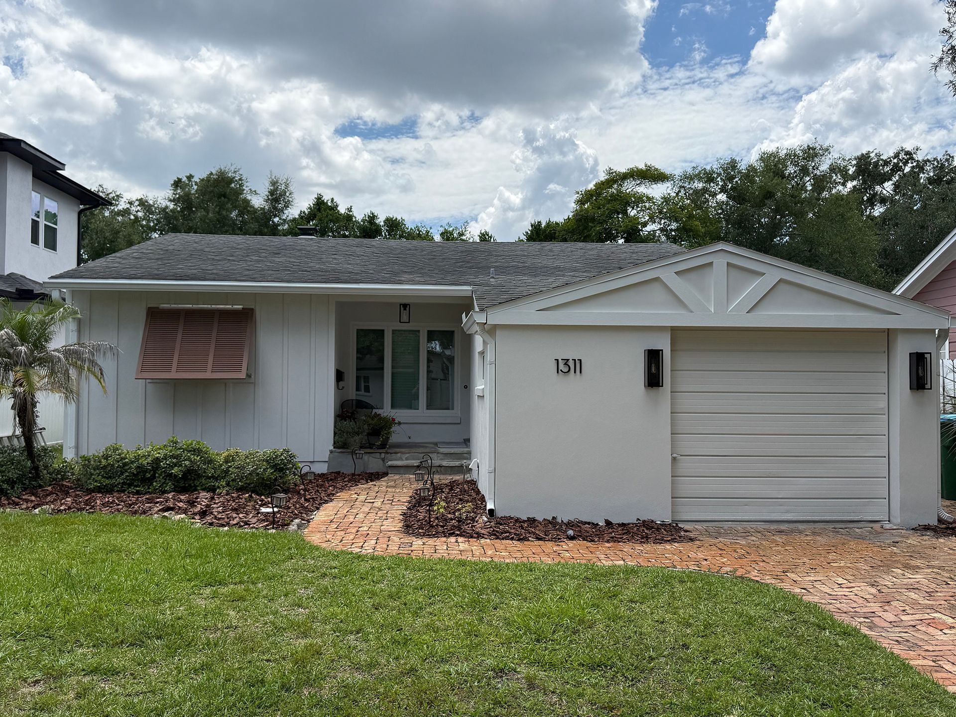 Single-story white house with garage, front lawn, and cloudy sky