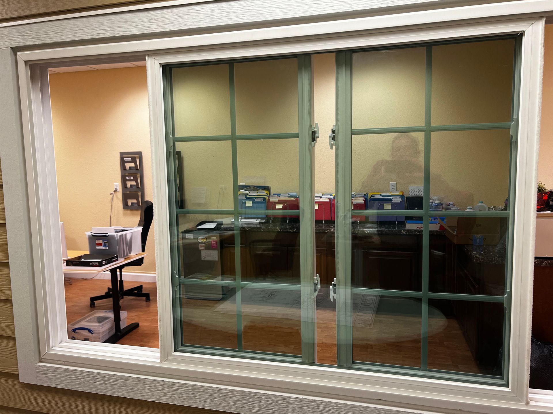 Office interior seen through a window with frosted glass panels and a desk inside