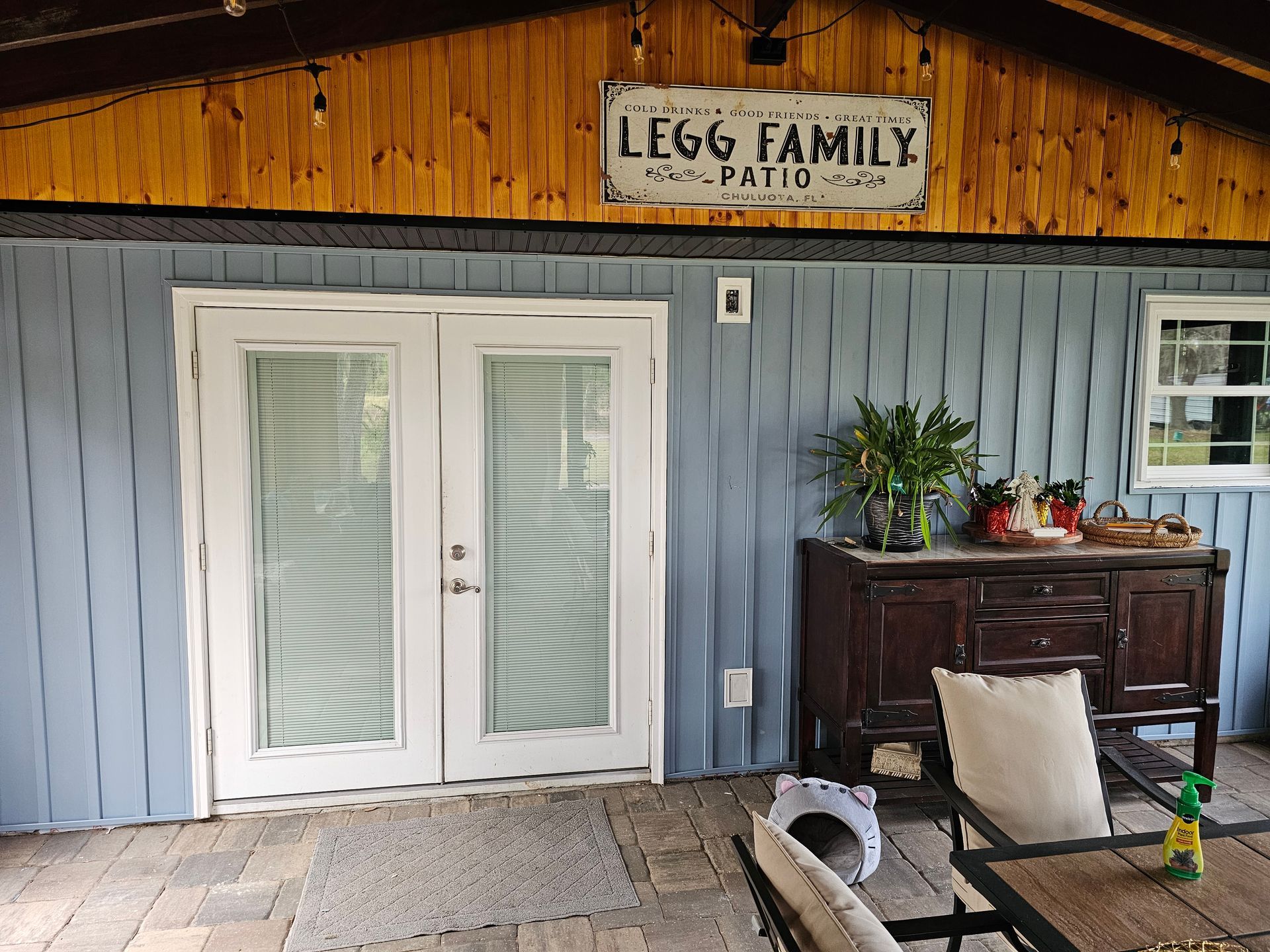 Patio outside a rustic building with blue siding, white French doors, and a sign reading “LEGG FAMILY.”