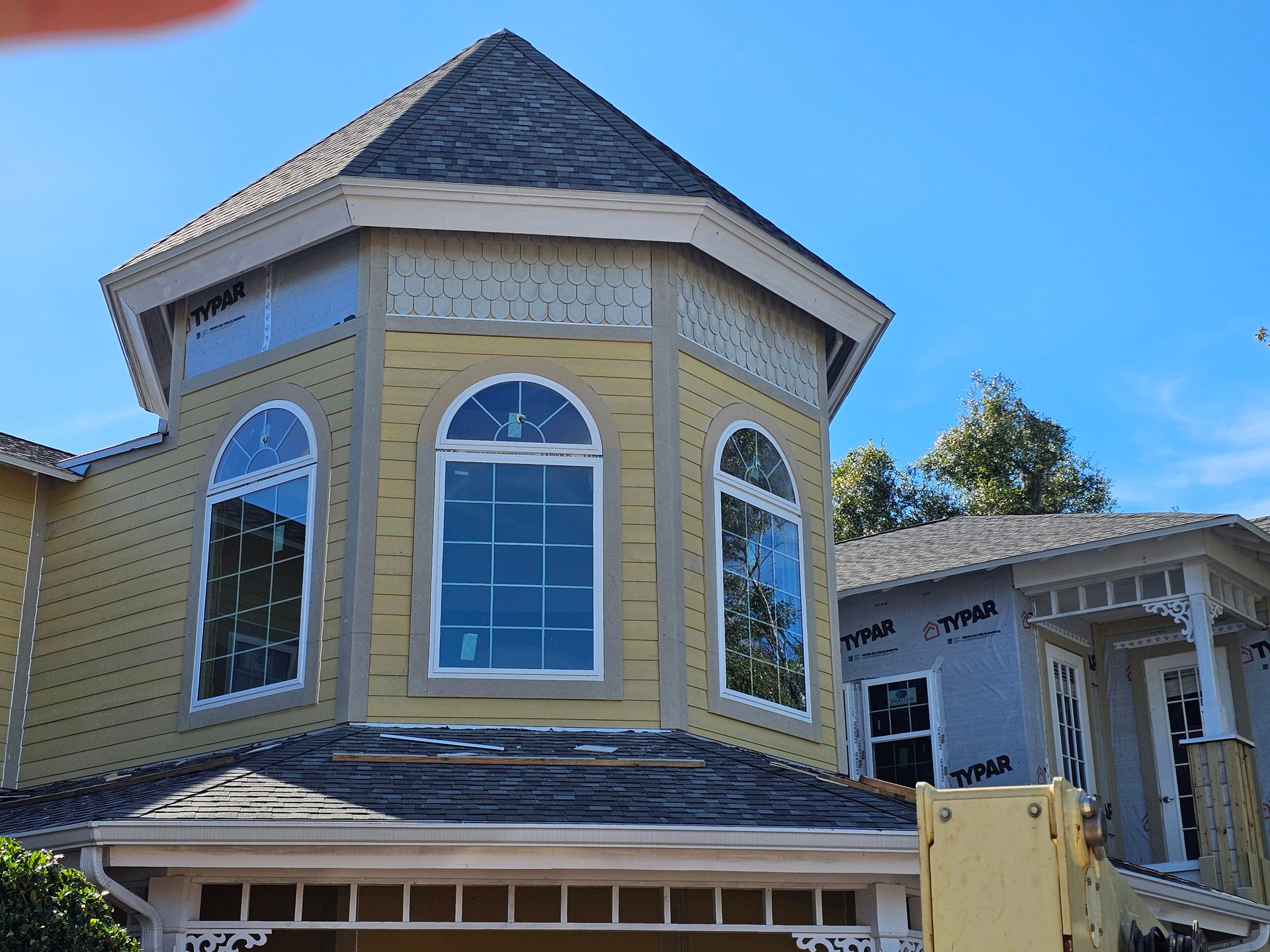 Yellow house with a turret and arched windows against a blue sky