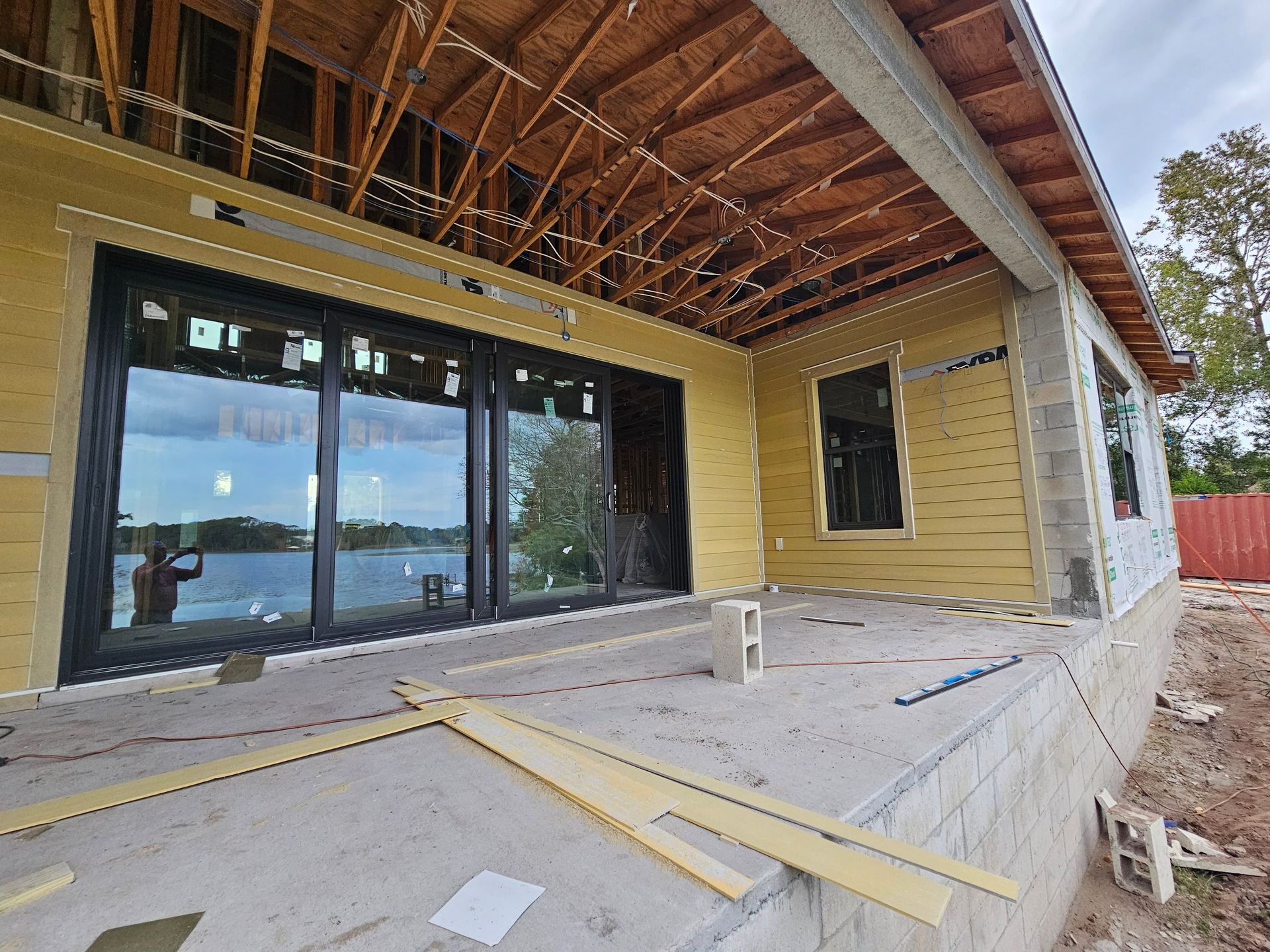 Partially finished patio with large glass doors, wood ceiling, and yellow exterior walls under construction
