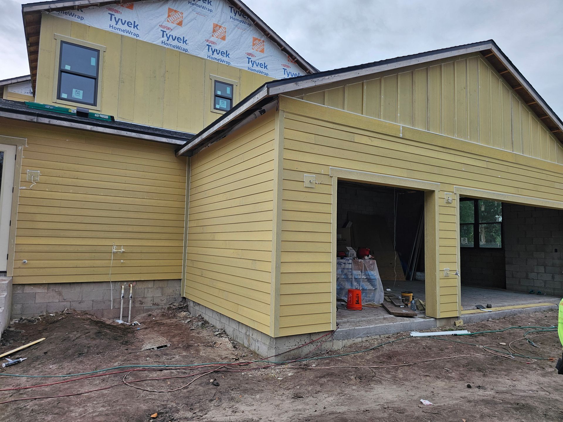 Yellow house under construction with unfinished siding and open garage bay