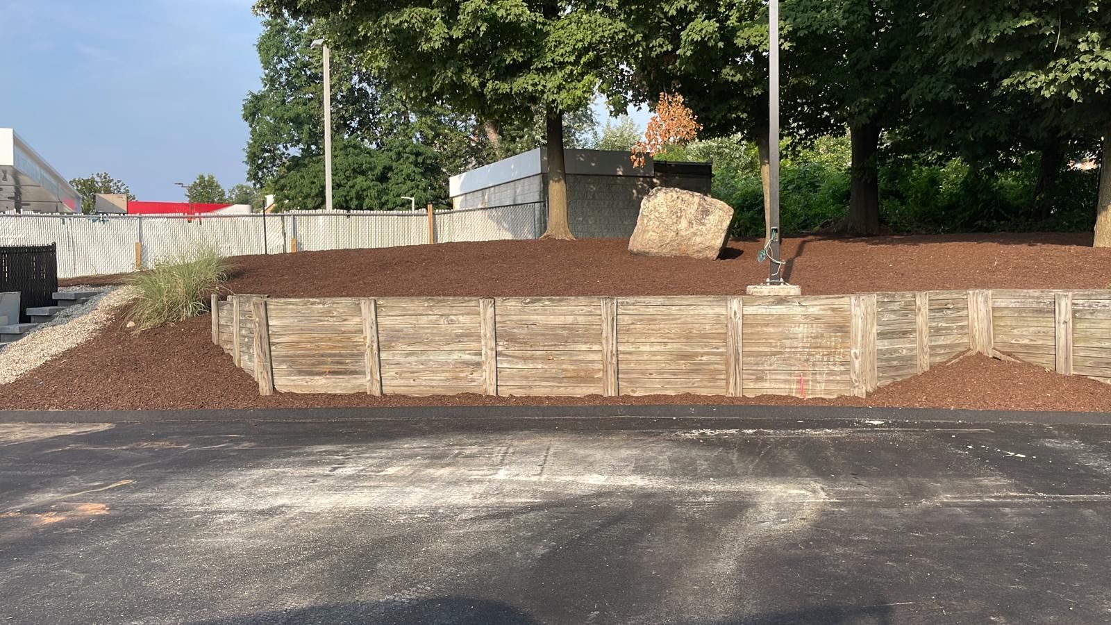 a pile of dirt is sitting on the side of a road next to a wooden wall .