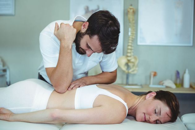 Massage therapist massaging a client&rsquo;s back in a spa treatment room