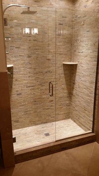 Shower with glass doors and beige tile walls.