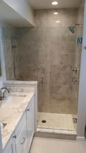 Bathroom with a glass shower enclosure and tiled walls. White vanity with granite countertop.