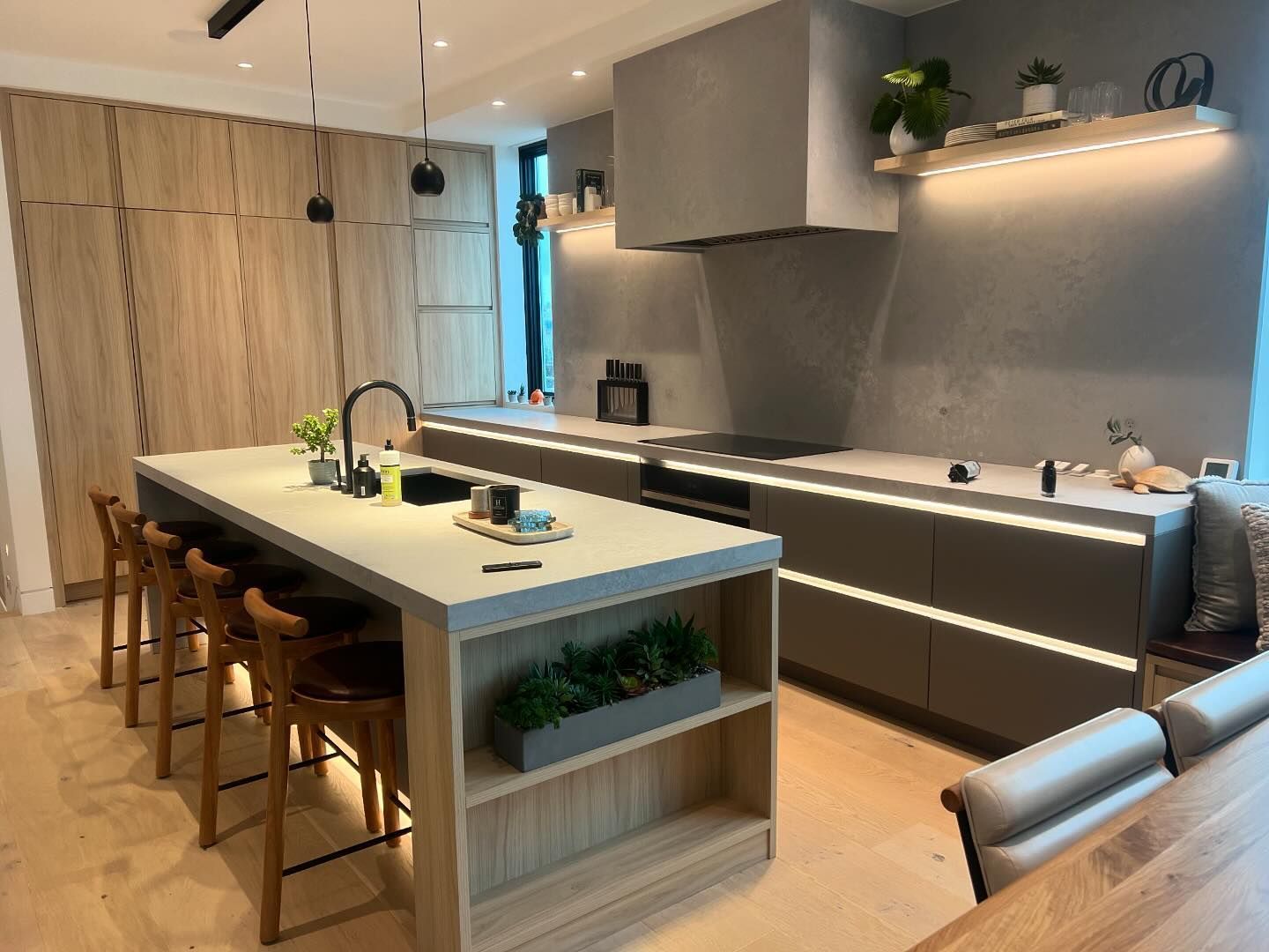 Modern kitchen with island, wooden cabinets, grey countertops, and stainless steel appliances.