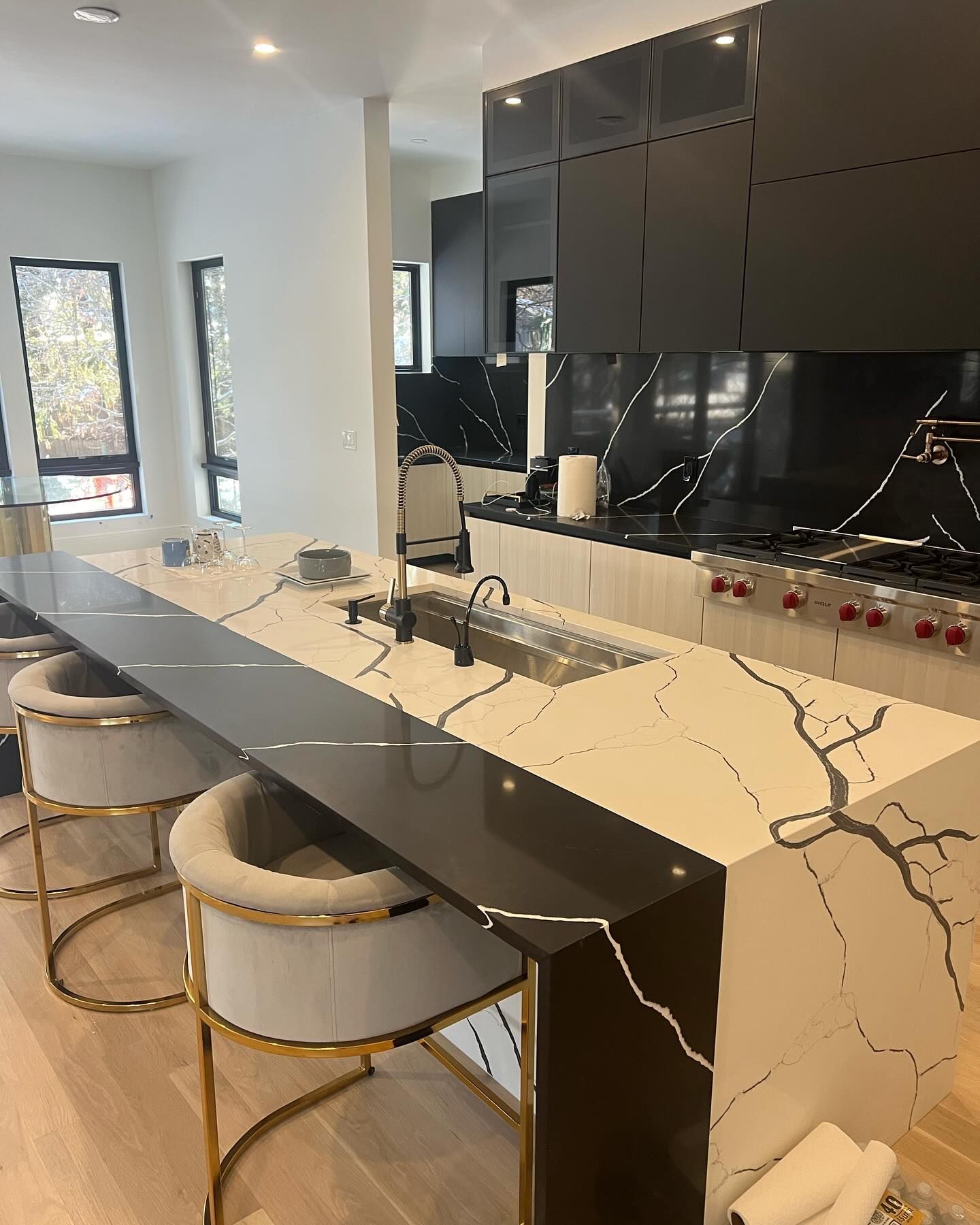 Modern kitchen with marble countertops, black cabinets, and bar seating.