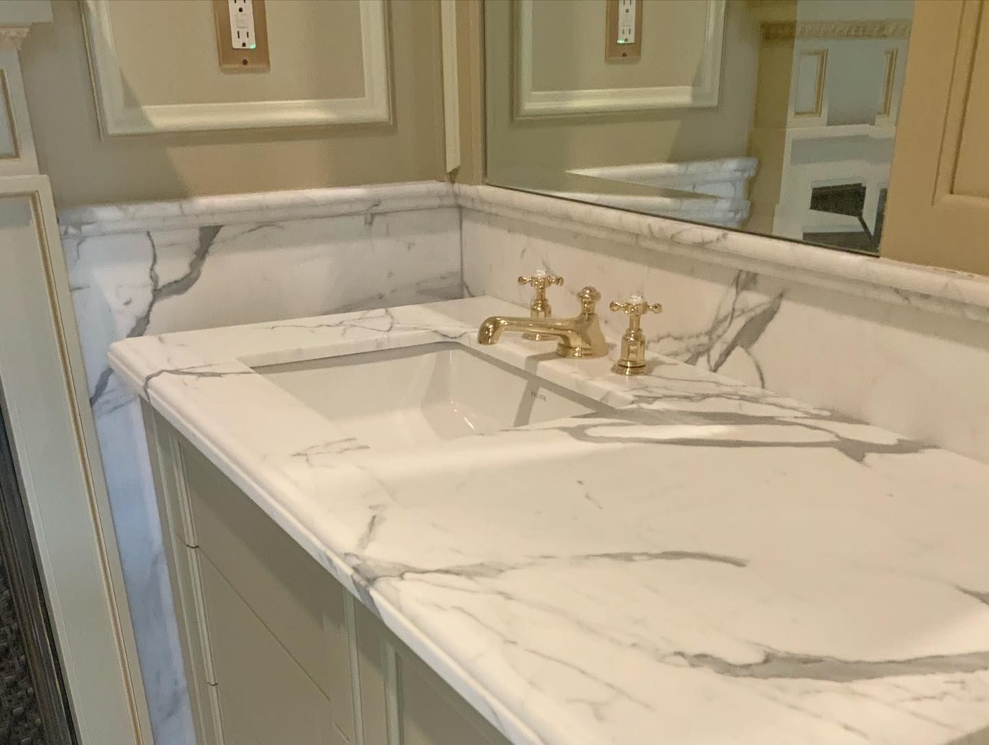 White marble bathroom vanity with gold faucet.