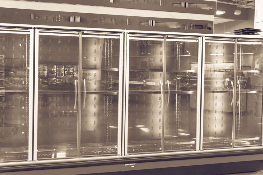 A black and white photo of a refrigerator with glass doors.