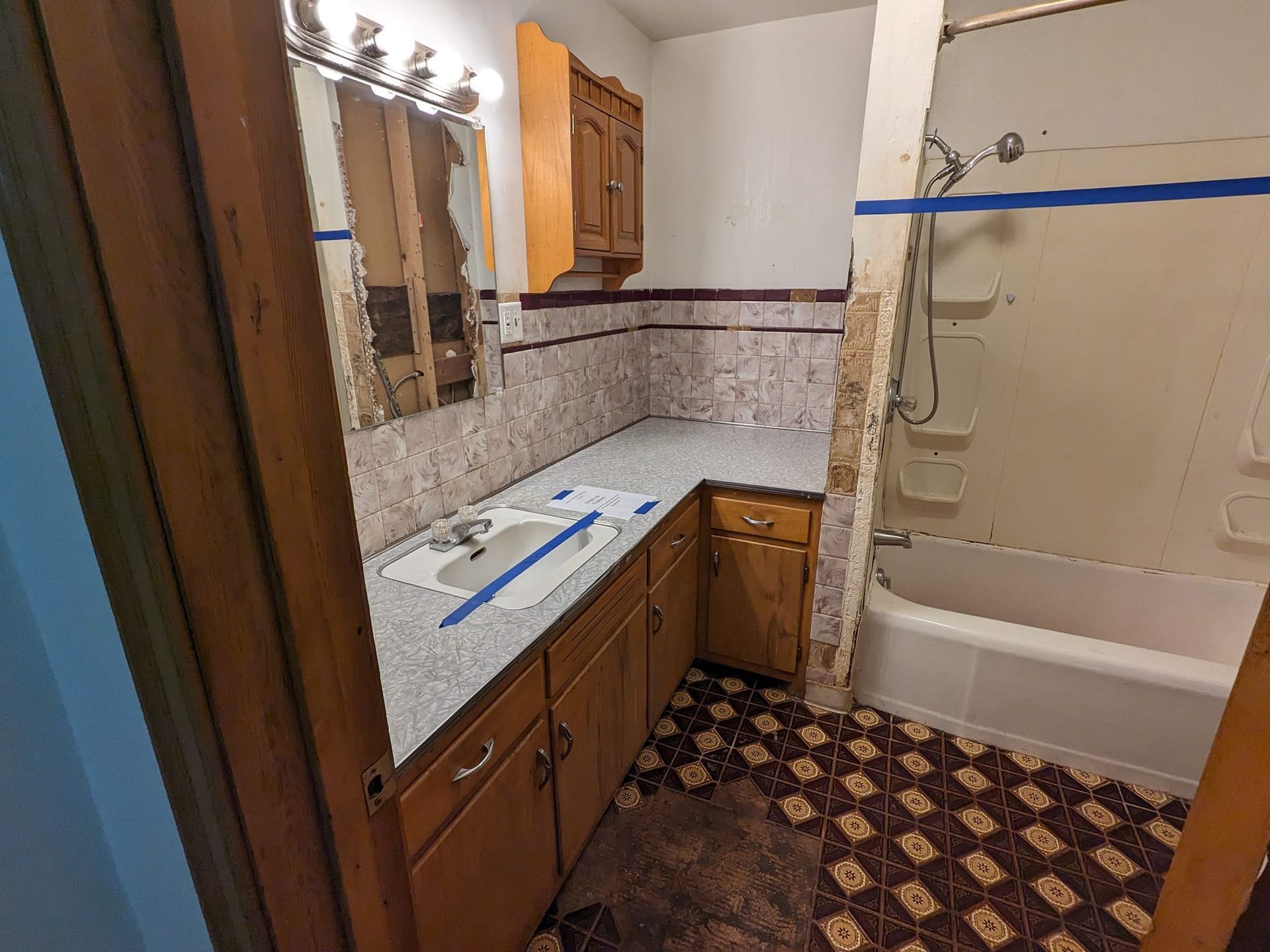 A bathroom with a sink , tub and mirror.