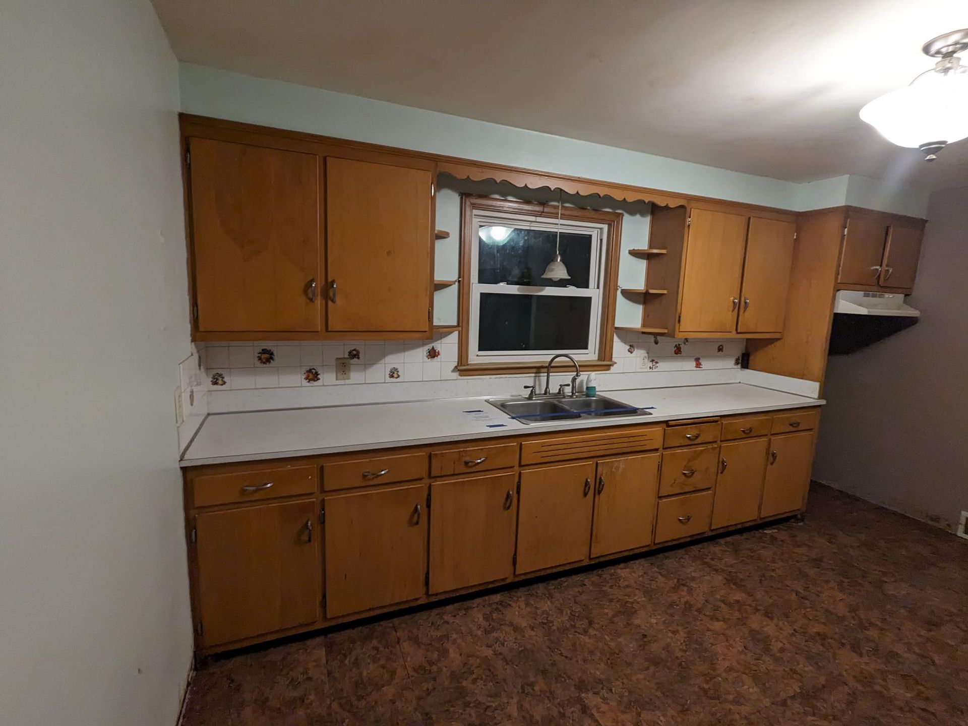 An empty kitchen with wooden cabinets and a sink.