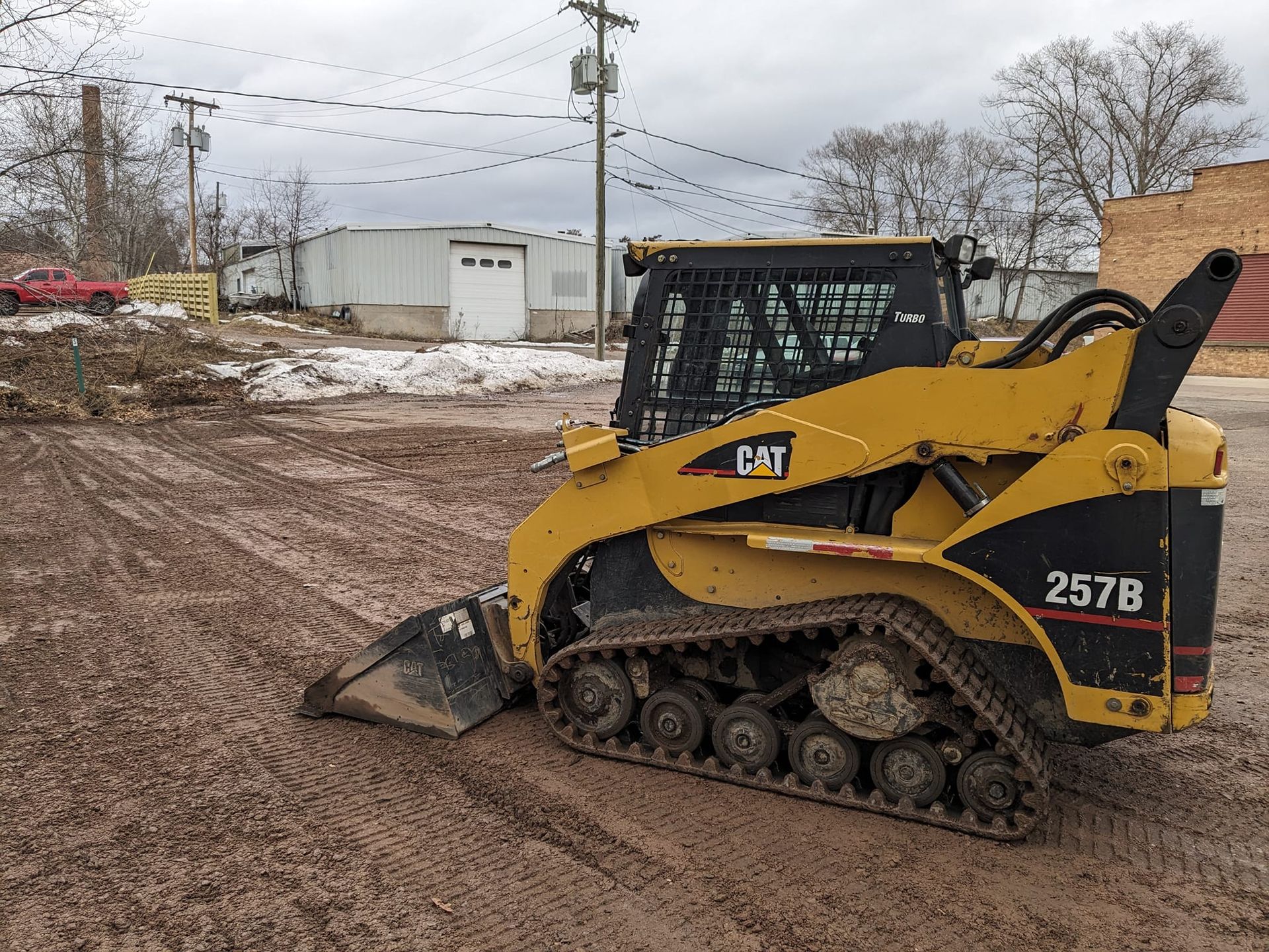 A yellow and black cat track loader is parked in a dirt field.