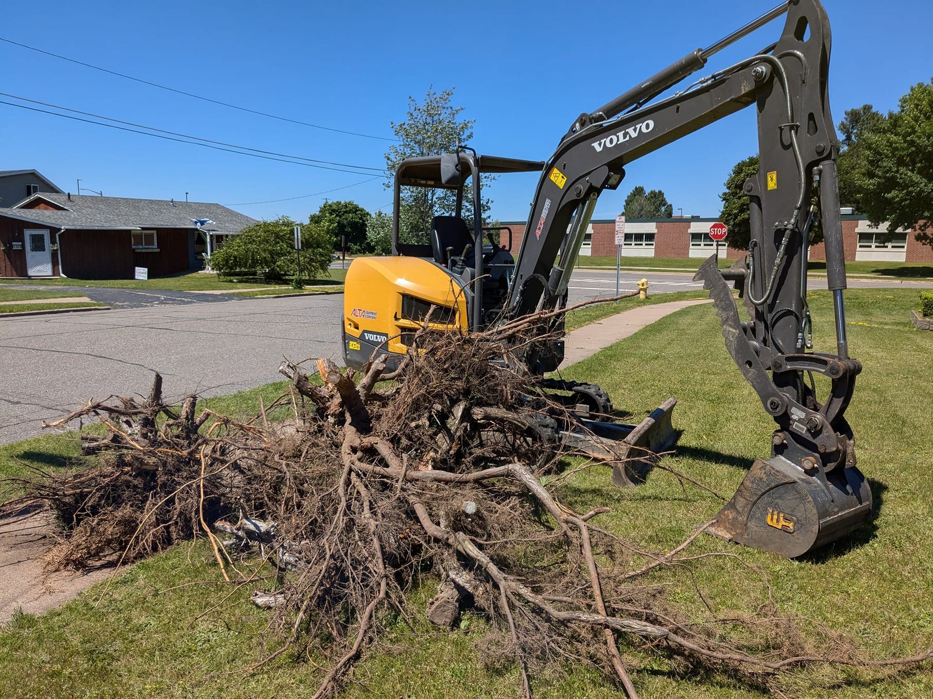 A volvo excavator is digging a hole in the grass.