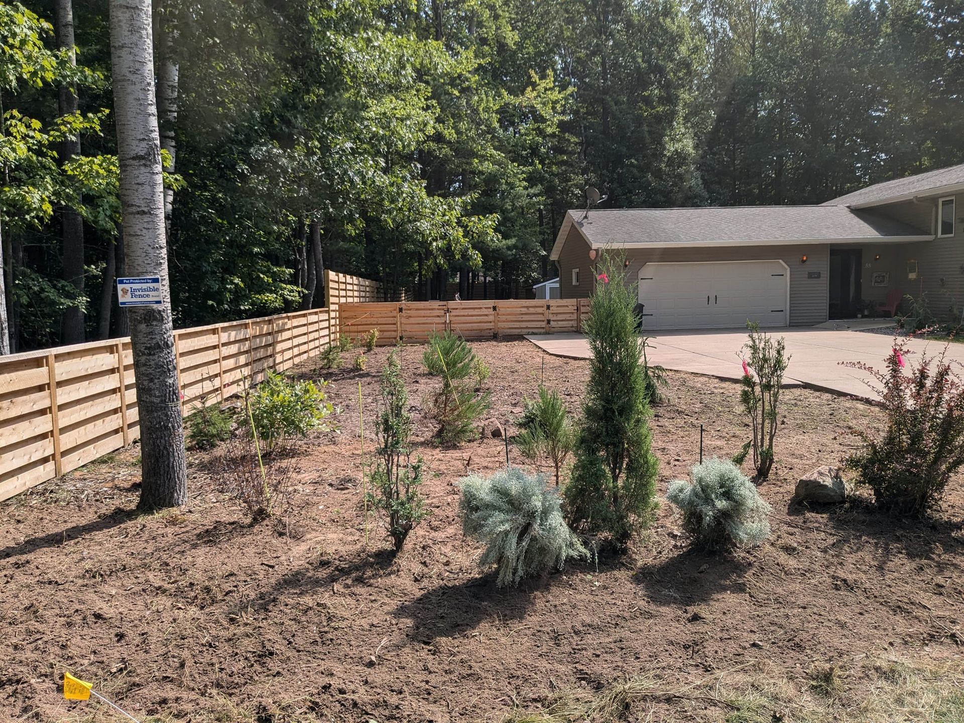 A house with a wooden fence and trees in front of it.
