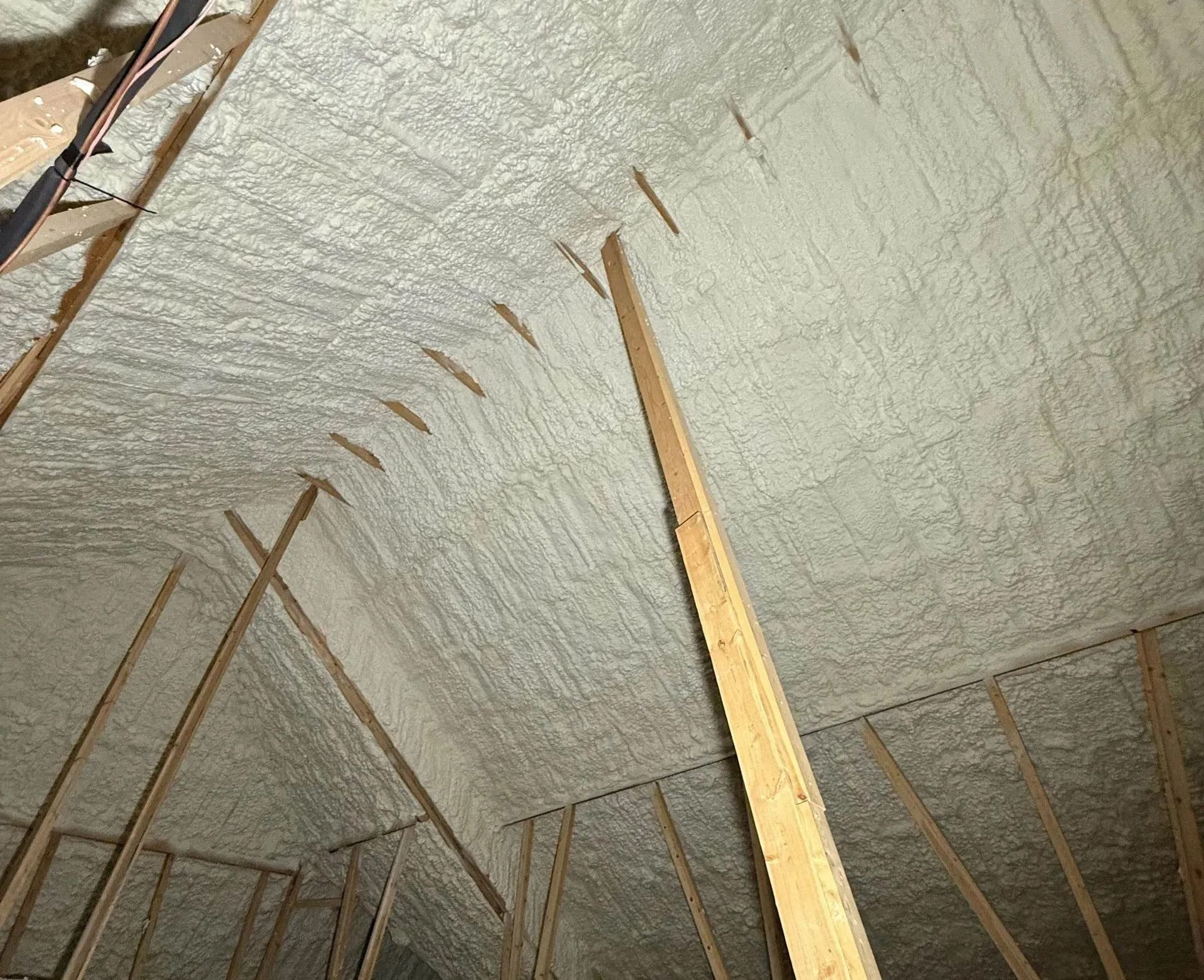 Attic interior with spray foam insulation covering the rafters and ceiling.